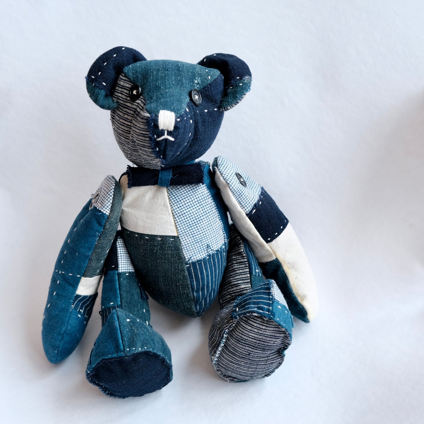 A handmade patchwork teddy bear crafted from antique indigo and French linen Boro scraps.