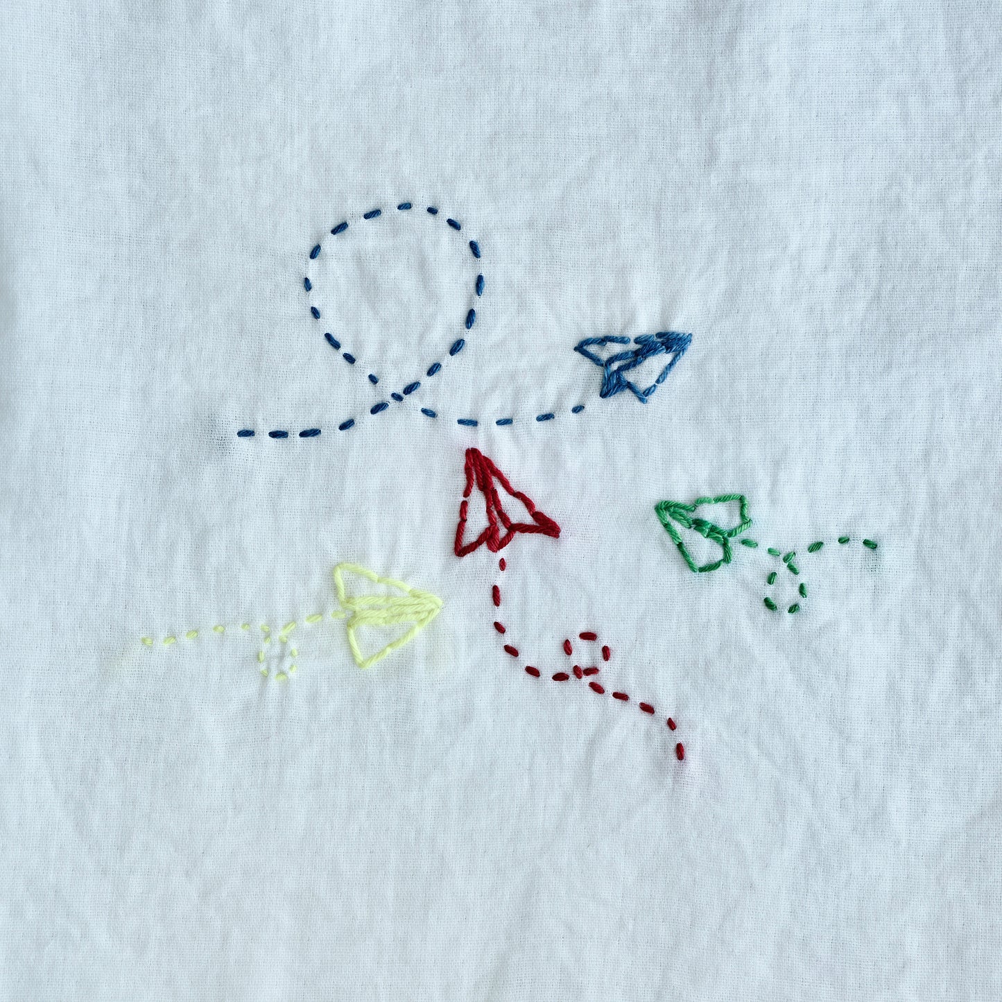 Finished Sashiko embroidery of an airplane for the letter A on white fabric.