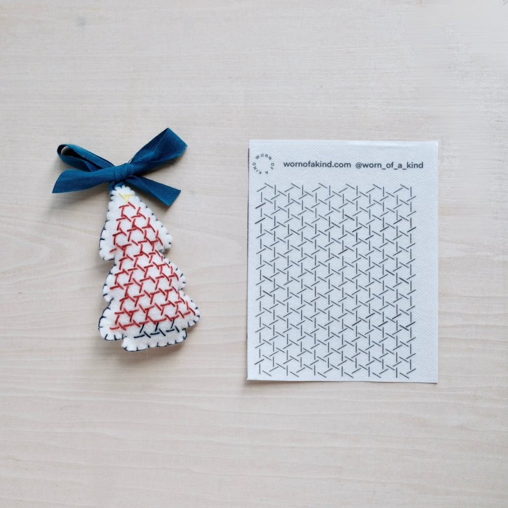 Wool Christmas tree ornament next to the Hitomezashi pattern transfer sheet used to make it.