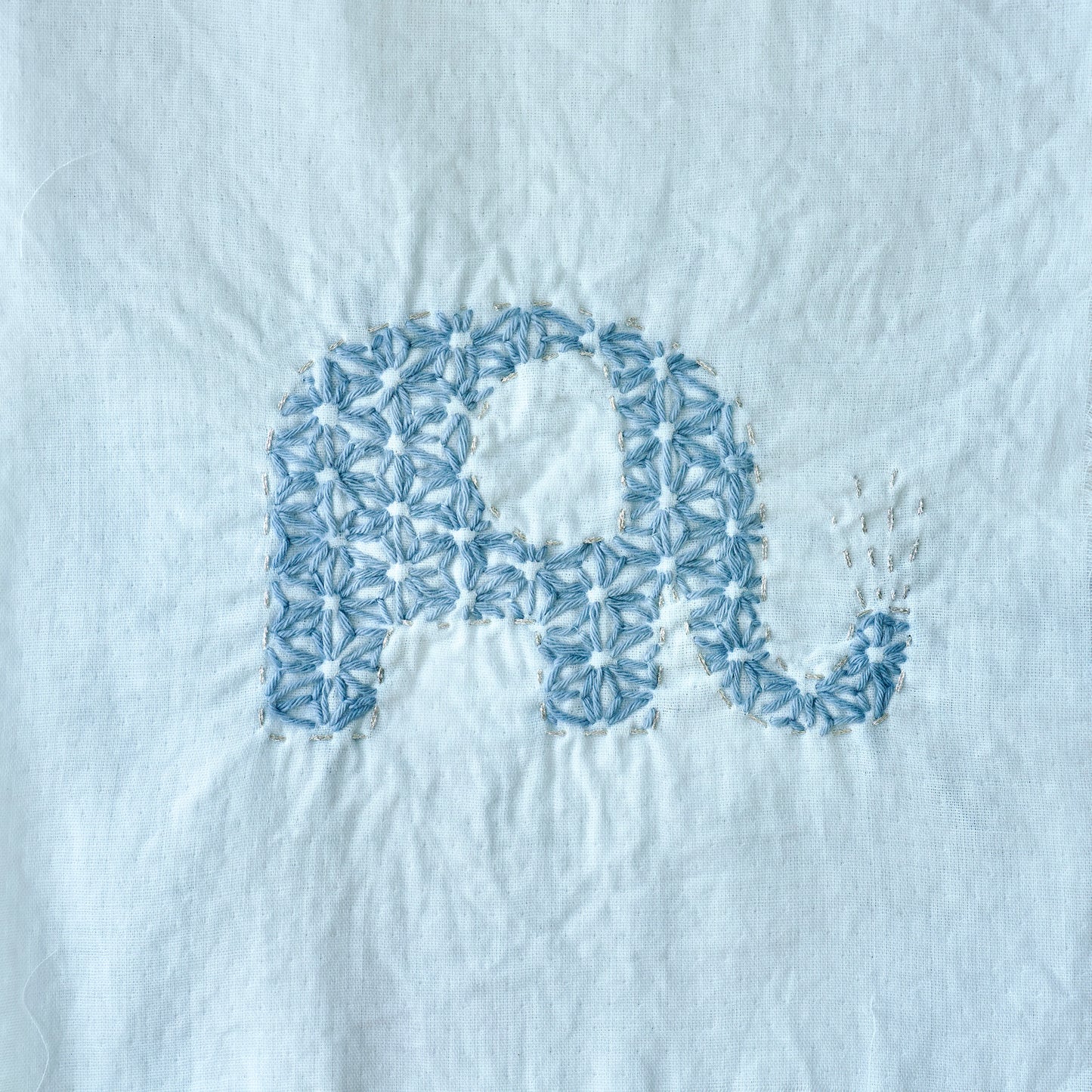 Hand-stitched elephant Sashiko pattern on fabric for the letter E.
