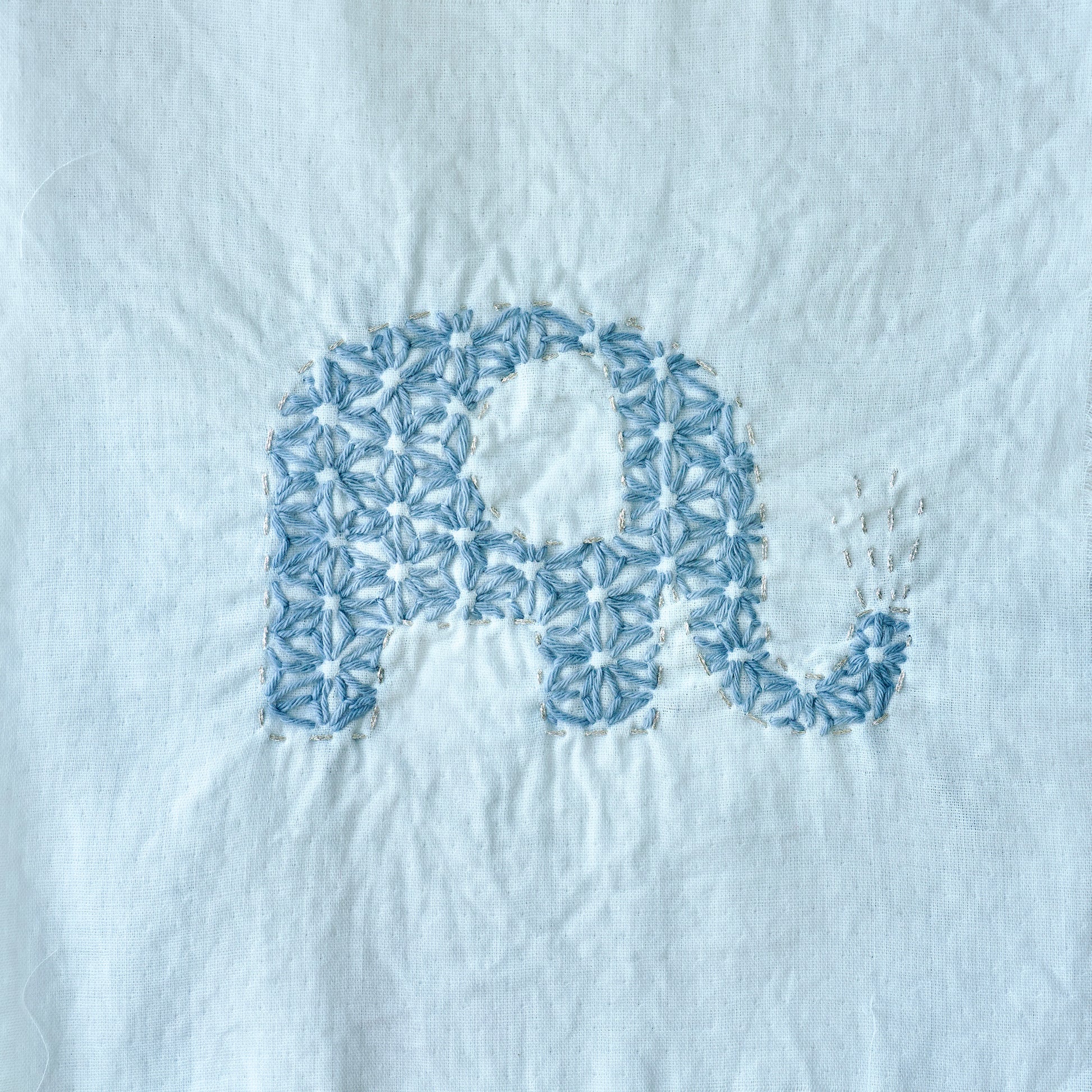 Hand-stitched elephant Sashiko pattern on fabric for the letter E.