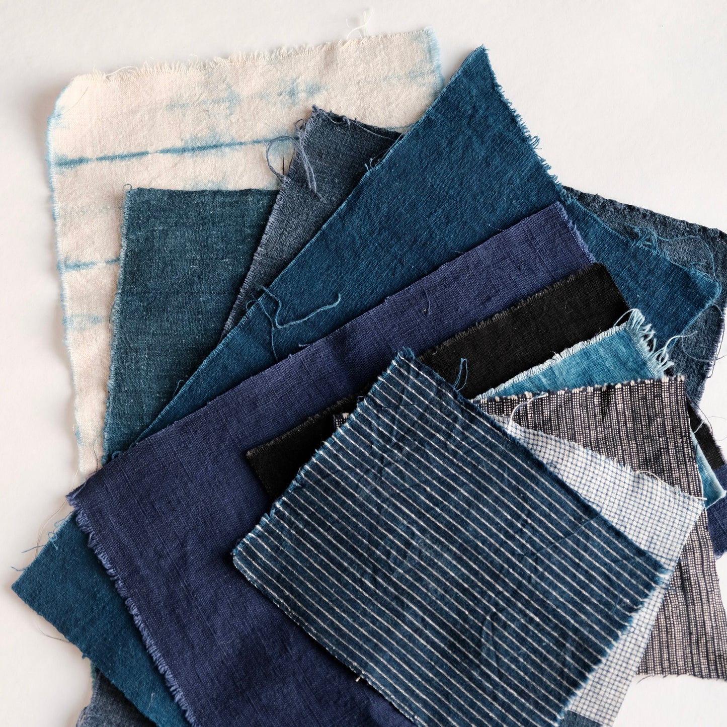 Detailed view of hand-dyed indigo linen and weathered cotton pieces showing unique textures.