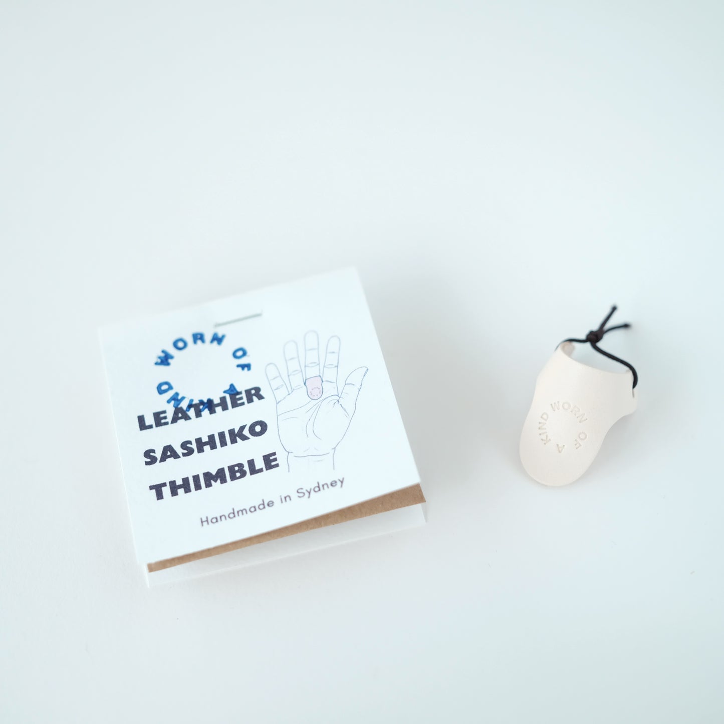 Handmade leather Sashiko palm thimble in Worn Of A Kind studio packaging.