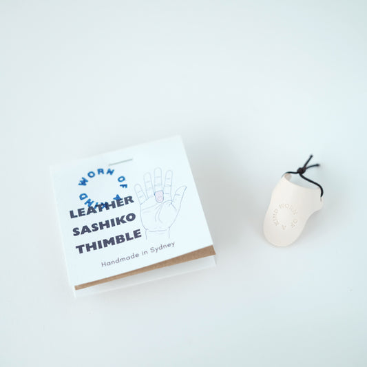 Handmade leather Sashiko palm thimble in Worn Of A Kind studio packaging.