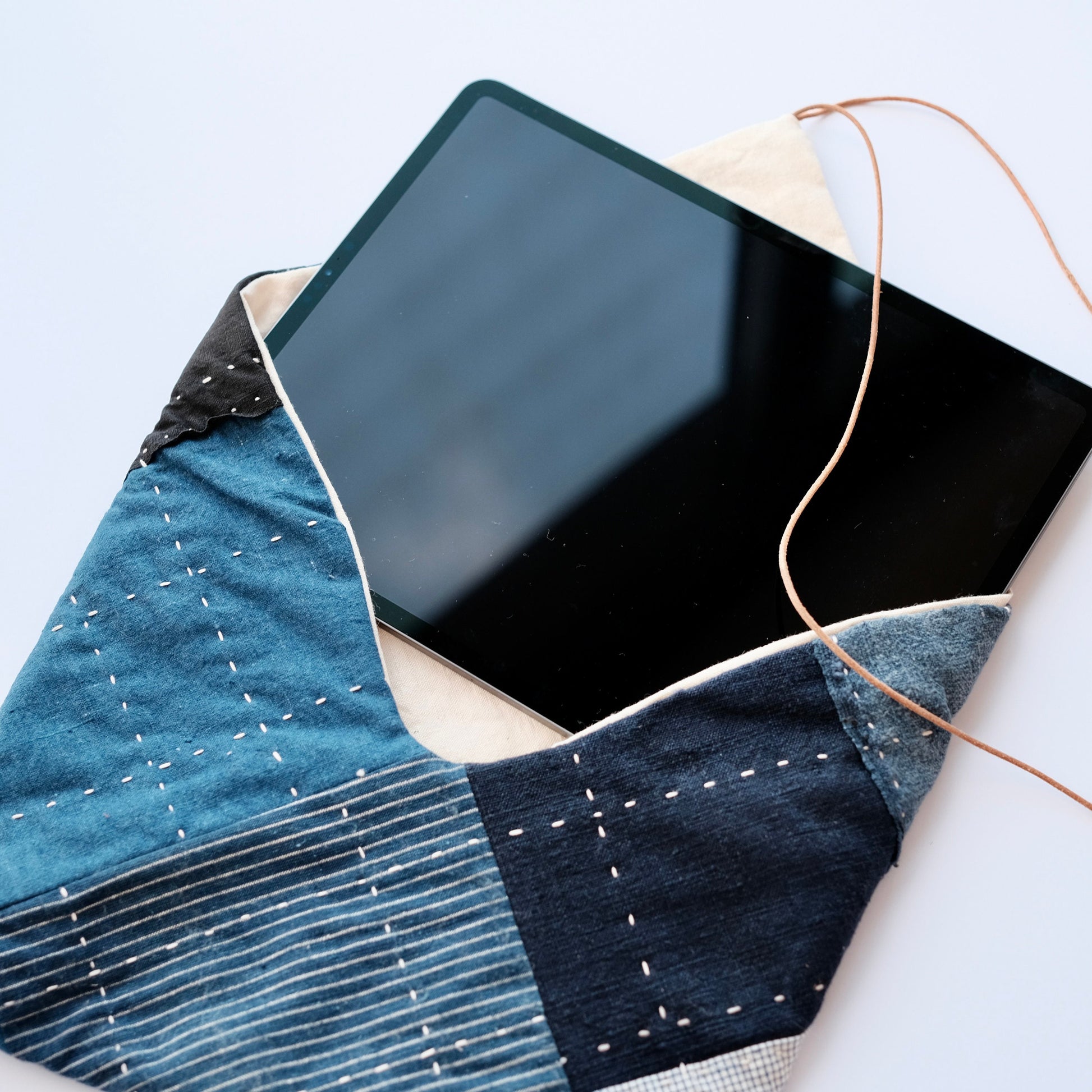 iPad Pro being removed from a handcrafted sustainable Boro patchwork sleeve.
