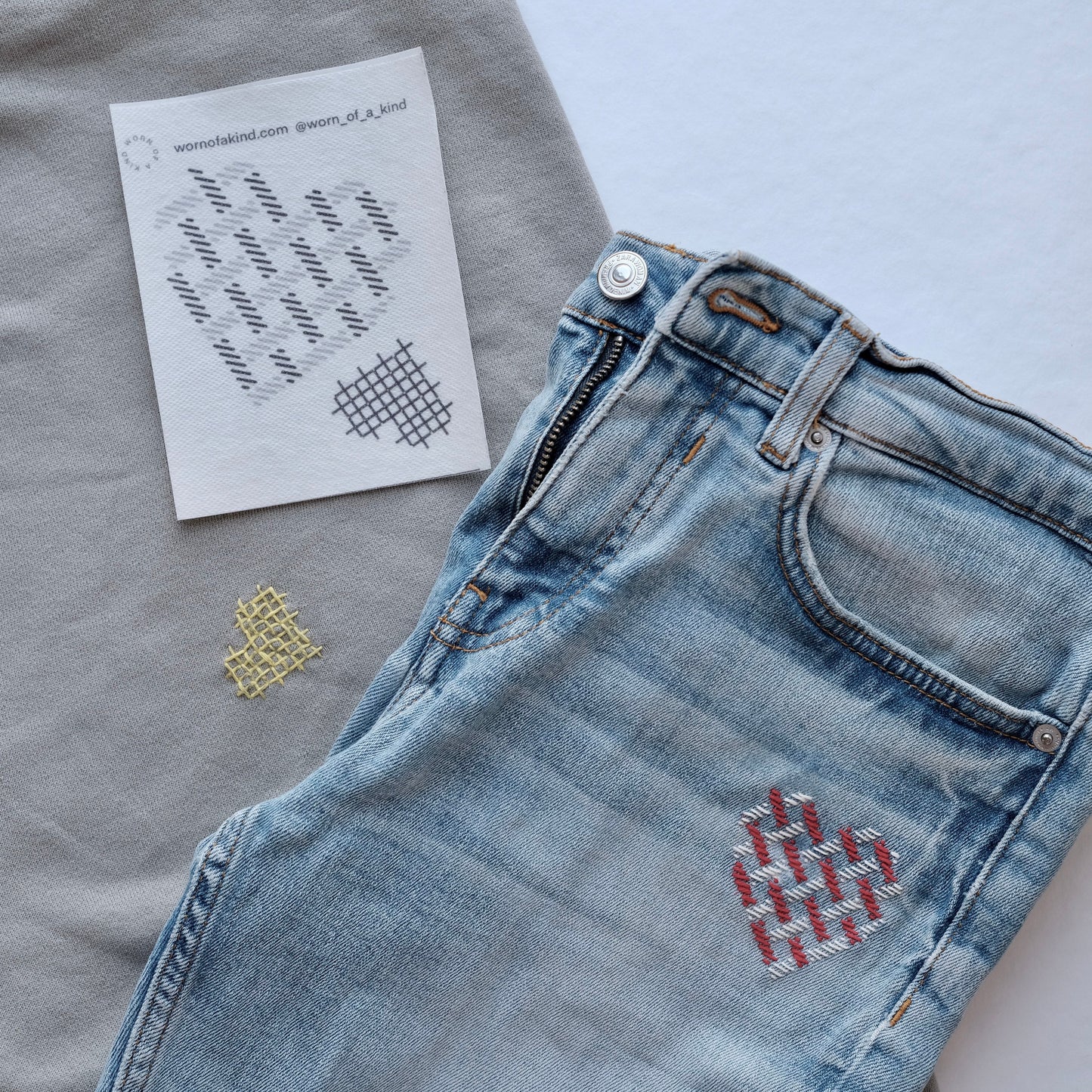Heart-themed Sashiko mending on a denim patch and a sweatshirt using the Love Mends kit.