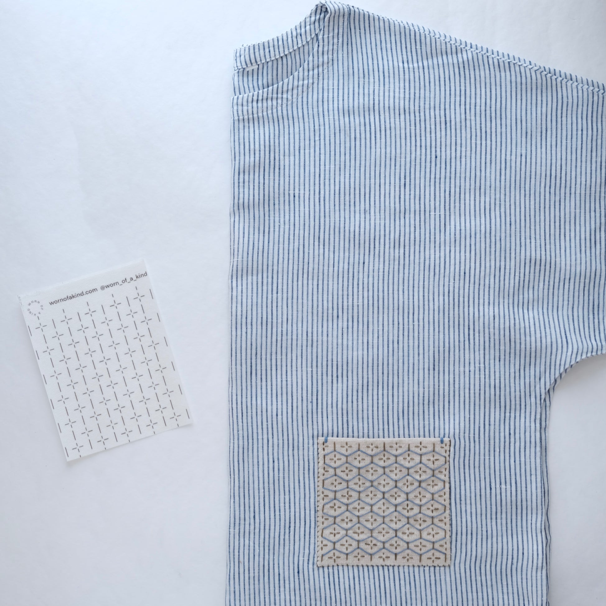 Close up of a finished Kugurizashi woven pattern on a linen top next to the base stitching transfer.