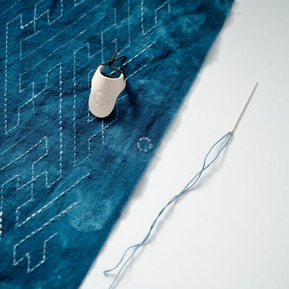 Leather palm thimble resting on a work-in-progress Sashiko mending project.