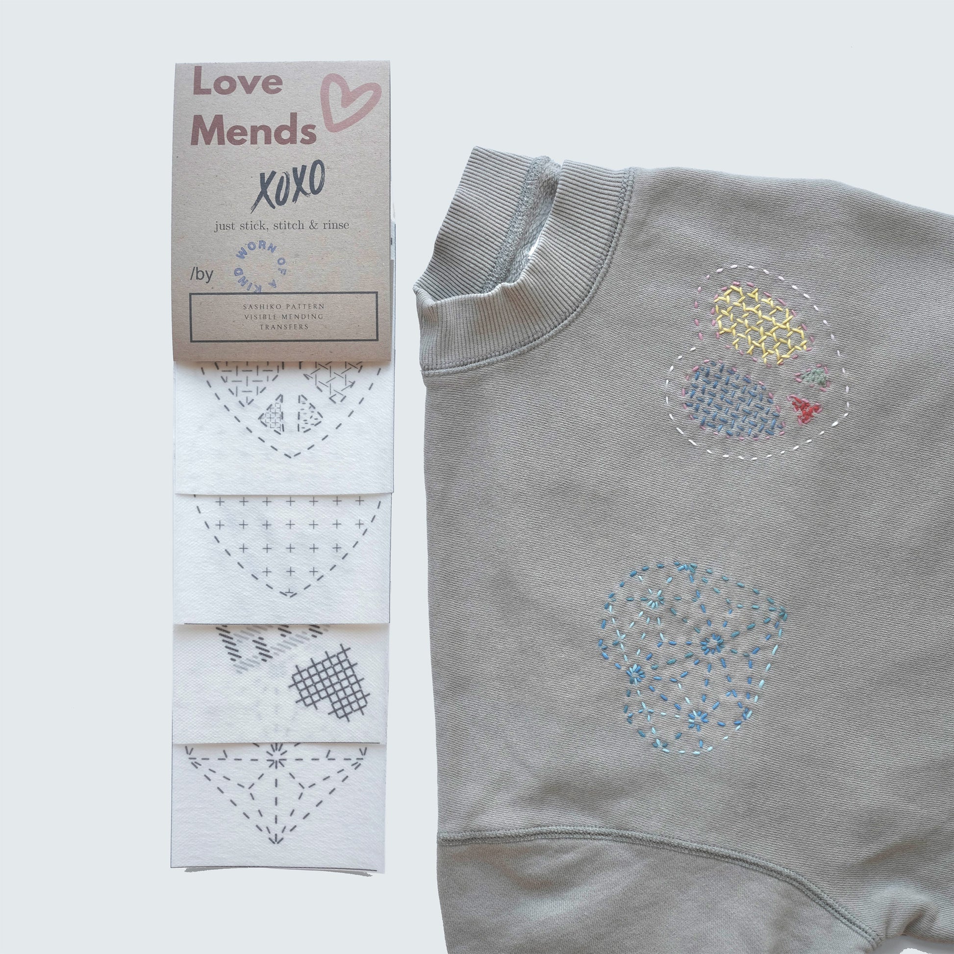 Love Mends Sashiko transfer set with heart-themed patterns sampled on a grey sweatshirt.
