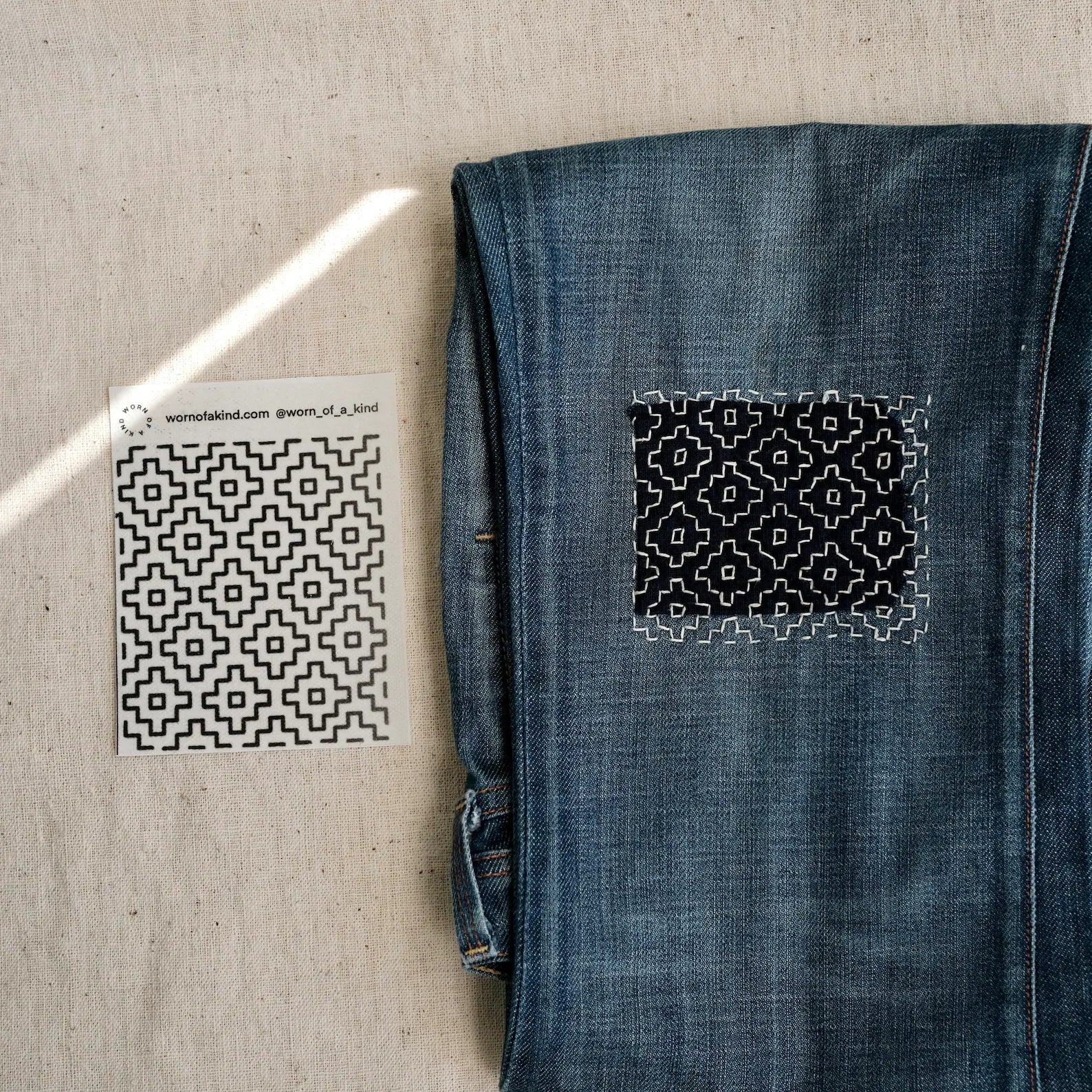 Close up of a Persimmon Flower (Kakinohana) Sashiko transfer sheet and finished denim repair.