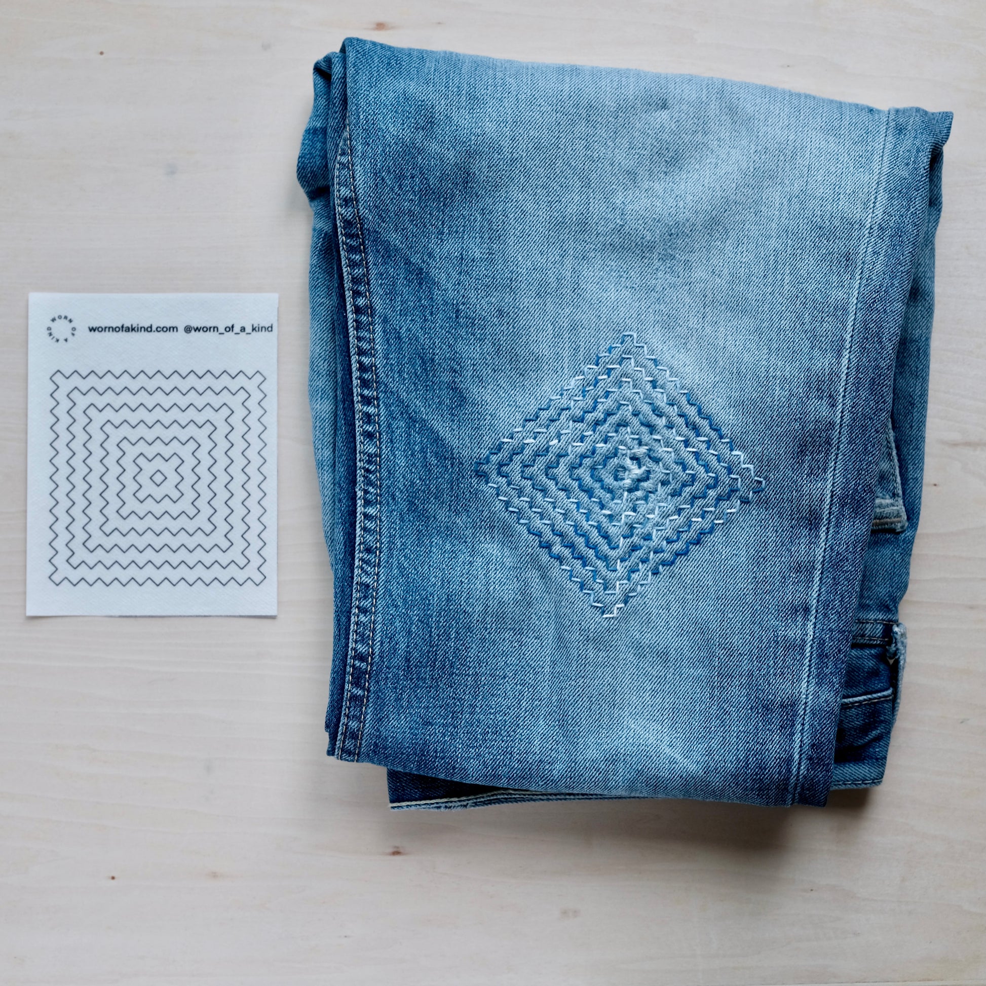 A single Persimmon Flower Sashiko transfer sheet next to a finished stitching sample on denim.