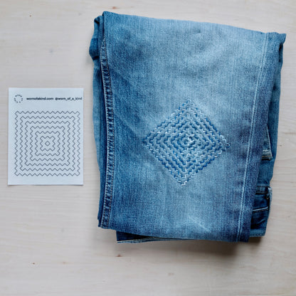 A single Persimmon Flower Sashiko transfer sheet next to a finished stitching sample on denim.