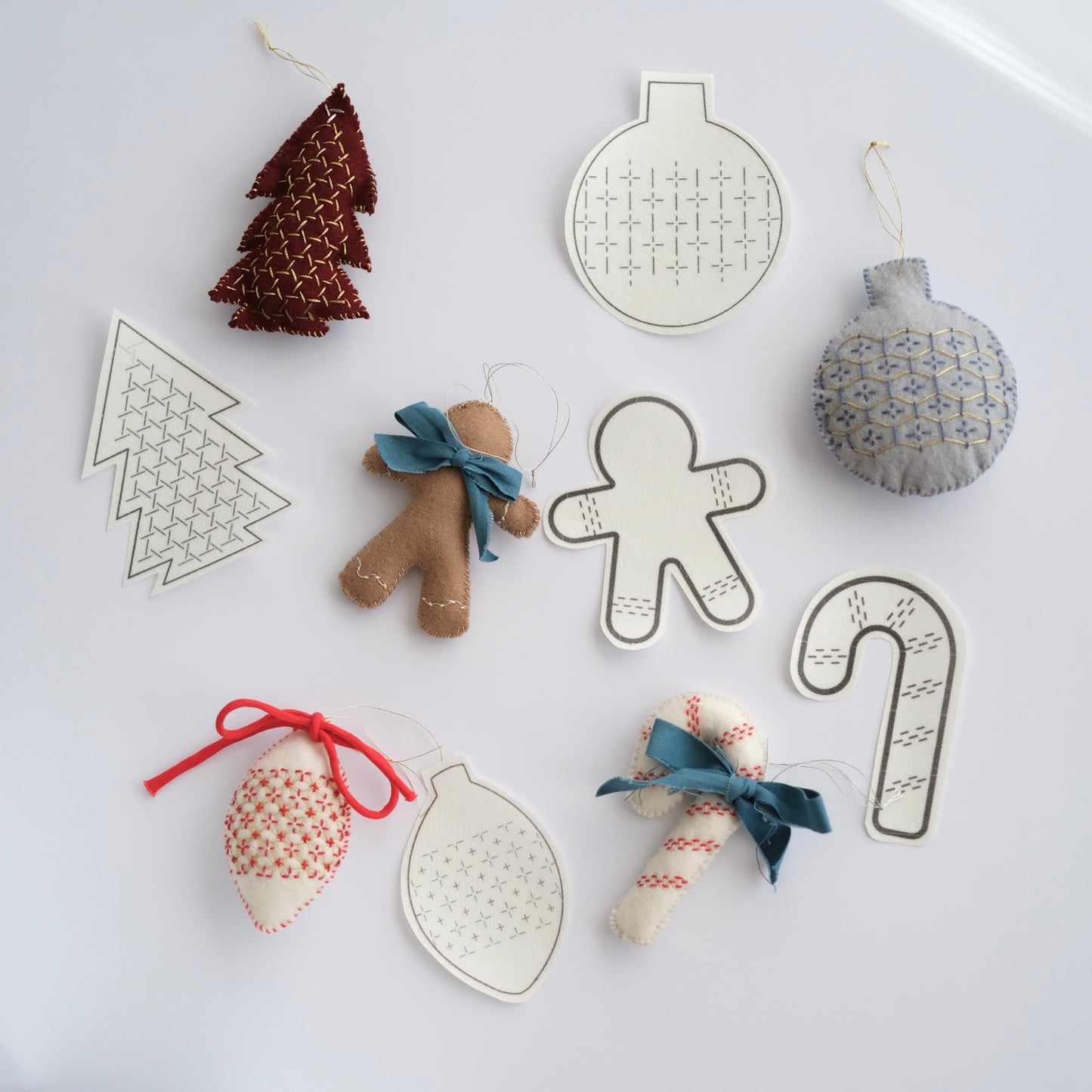 Collection of 5 Sashiko ornament transfers alongside finished festive felt decorations.