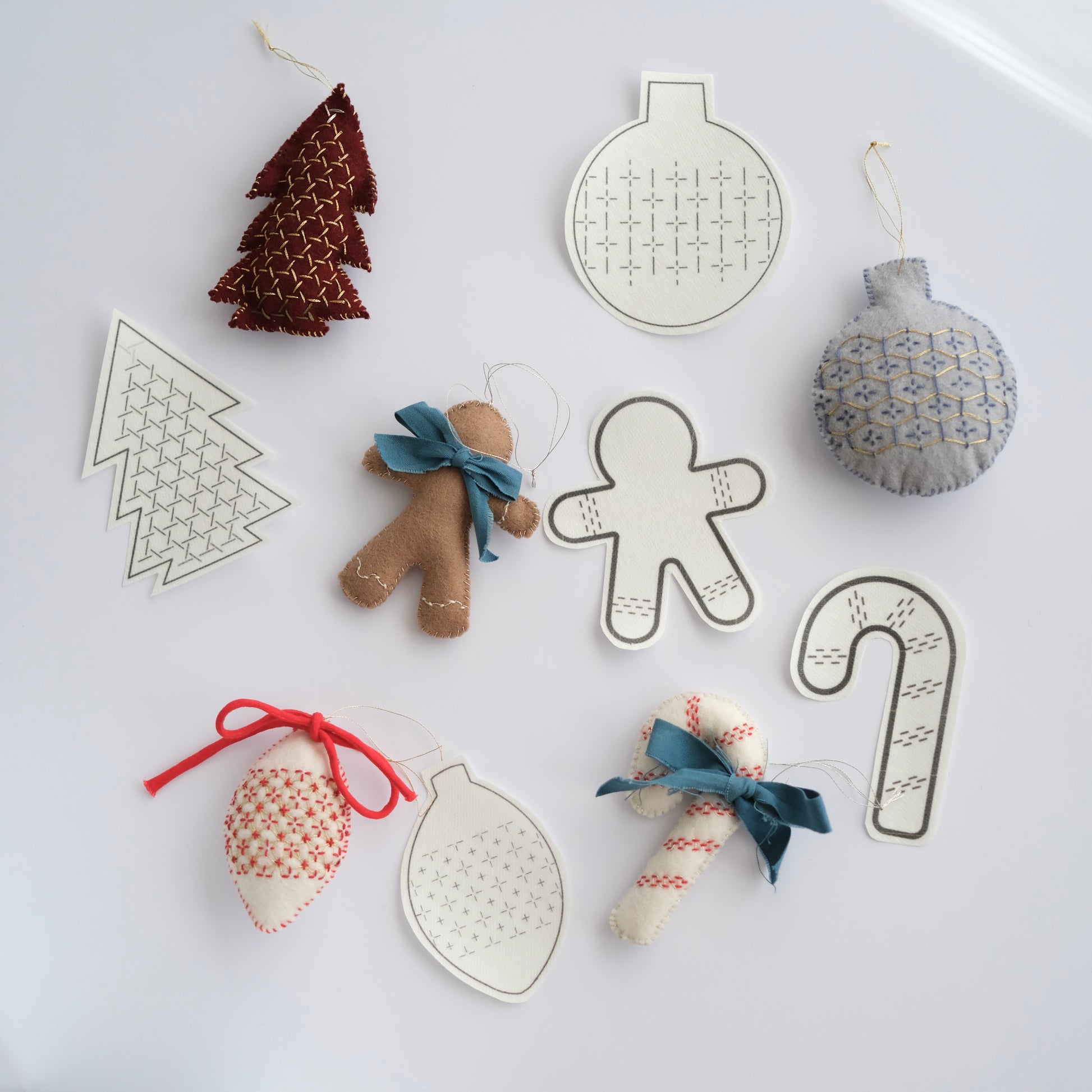 Collection of 5 Sashiko ornament transfers alongside finished festive felt decorations.