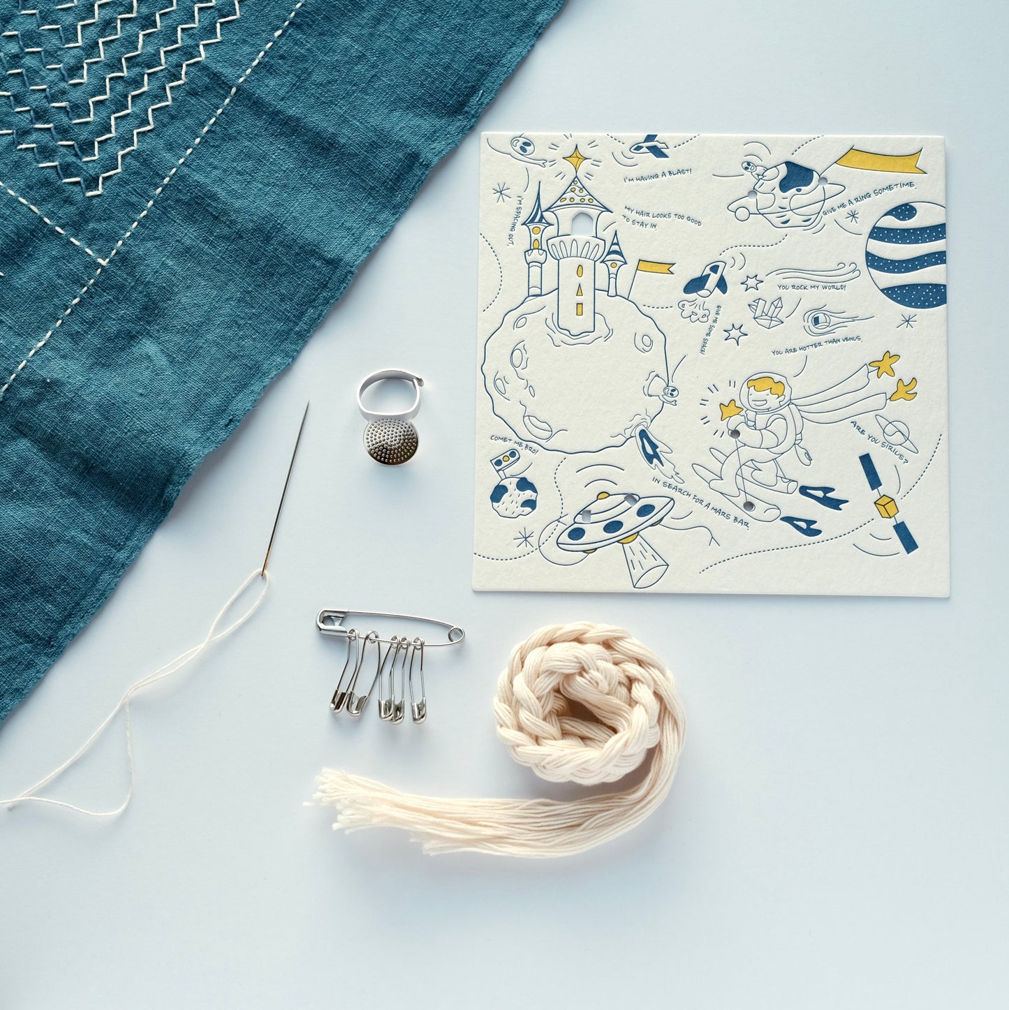 Sashiko tool set arranged with an indigo fabric sample and the artist-designed letterpress carrier card.