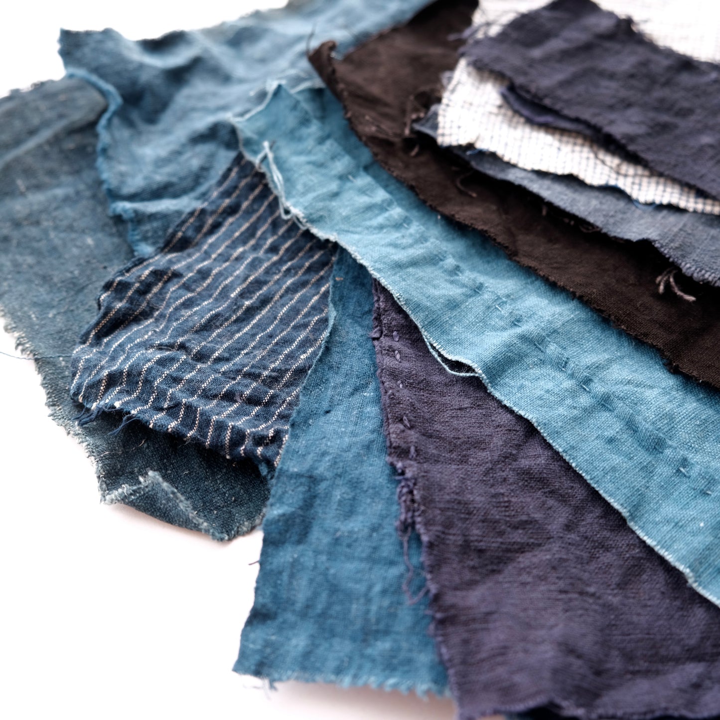Close-up stack of various indigo-dyed and hand-woven antique fabrics for patchwork.