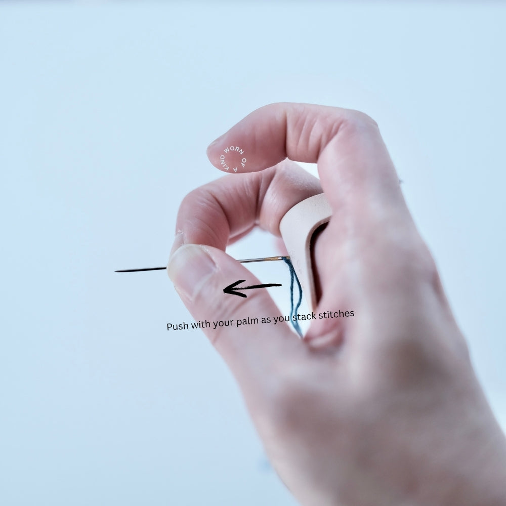 Hand wearing the leather thimble in the traditional Unshin stitching position.