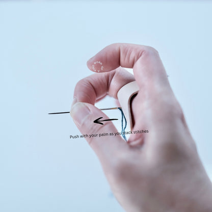 Hand wearing the leather thimble in the traditional Unshin stitching position.