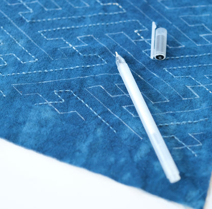 White heat erasable pen marking a Sashiko pattern on indigo fabric.